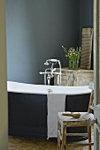 An antique bathtub with free-standing taps against a dark-grey wall