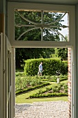 Blick durch die Tür in den Garten, Gärtner pflegt angelegte Rabatten