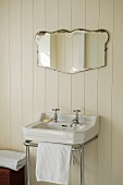 A wash basin with a chrome towel rail and a mirror on white wood panelling