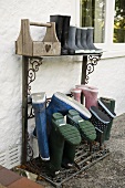 Wellie boots on a rack against the wall of a house