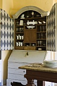 An old fashioned crockery cupboard with a checked pattern inside the doors