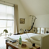 A fitness machine in a simple bedroom with a slopping roof