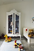 A minimalistic children's bedroom - a child's bike in front of a white-painted antique cupboard