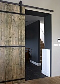 A rustic wooden sliding door from a hallway into a designer apartment