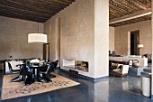 An open-plan dining room with black, plastic chairs and a view into a living room in a Mediterranean country house