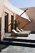 Neubauhaus in Marokko - Liegestühle auf betonierter Terrasse mit Sonnensegel vor Fenster