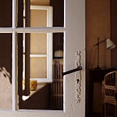 An old glass door with a white wooden frame and a wrought iron handle