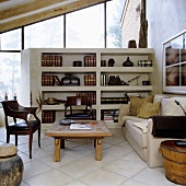A living room with large windows and a seating corner in front of a stone shelf acting as a room divider