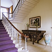 An elegant flight of stairs with a wrought iron banister and an antique washstand underneath