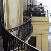 A curved balcony railing on the facade of an urban villa