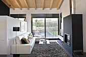 A designer living room with a view of the garden - a leather sofa in front of a partition wall in front of a black fireplace