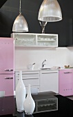 White vases on a black shelf and a kitchen counter with 1950s-style devices against a black wall