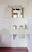A corner of a bathroom - a designer washstand with a mirror and lights