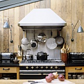 An old kitchen oven hung with pots against a wooden wall