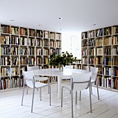 A round table in front of floor-to-ceiling book shelves on white floor boards