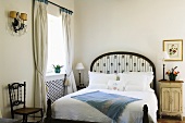 A queen-size bed at the window in a bedroom in country house