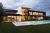 Evening atmosphere - an illuminated villa with a glass facade and a pool