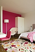 Boudoir - Teppich mit Blumenmuster und Sessel mit weisser Stehlampe vor pinkfarbener Wand