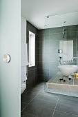 Blick in grau gefliestes Designerbad mit Waschschüssel auf Ablage