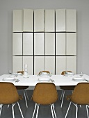 Gedeckter Tisch mit braunen Schalenstühlen und massgefertigtem Wandschrank mit offenen Türen