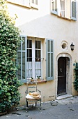 A facade of a country house with bars at the windows and a straw hat on a chair