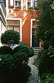 A house with a red facade and a path into a green rear courtyard