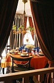 A view through a curtain - a chandelier with a green shade above a laid table