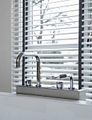 Designer bath taps in front of a window with half open blinds