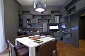 Designer Wohnraum in Grau - weisser Tisch und Metalllampenschirm vor Wand mit Einbauregal