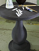 Black bistro table with paint tubes and paint brushes