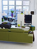 Green sofa and black upholstered stool with white entertainment center in front of patio doors