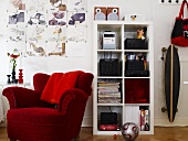 Red upholstered chair and white shelves and a skateboard on the wall