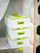 Beschriftete Boxen aus Kunststoff im Regal mit weißem Stoffbezug