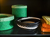 Green basket set next to black and white patterned wicker bowls on a black surface