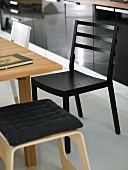 Schwarzer Küchenstuhl und heller Hocker aus Holz mit Polster