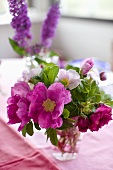 Pink flower bouquet in a glass vase on a pink surface