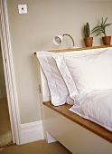 A detail of a modern bedroom with a platform bed, white bed linen