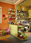 Green central island unit in orange kitchen with cluttered shelves
