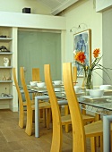 Glass dining table and wooden chairs with table laid for dinner