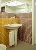 Badezimmerecke mit freistehendem Waschbecken vor gelben und braunen Mosaikfliesen