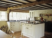 Open plan fitted kitchen and island unit with granite worktops and windows.