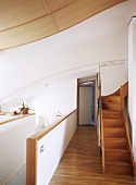 White kitchen area, stairs leading to another room and wooden flooring