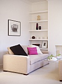 Upholstered sofa with black and pink cushion with shelving in recess