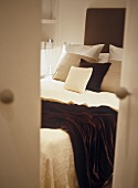 Blick durch offene Türe auf Doppelbett mit Kissen