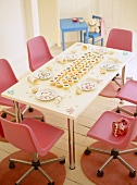 Geburtagsdeko und Cupcakes auf Tisch mit rosafarbenen Drehstühlen