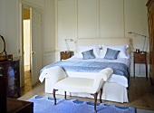 Blue and white bedroom with antique furniture an panelled walls.