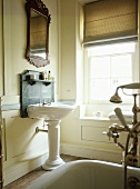 Bathroom with panelled walls and pedestal washbasin with marble spashback.