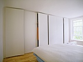 Modernes weisses Schlafzimmer mit Einbauschrank neben Fenster