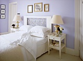 A traditional, pale blue bedroom with double bed, decorative headboard, side tables, lamps