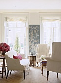 A traditional sitting room, upholstered sofa and wing back armchairs, French doors, wall hanging